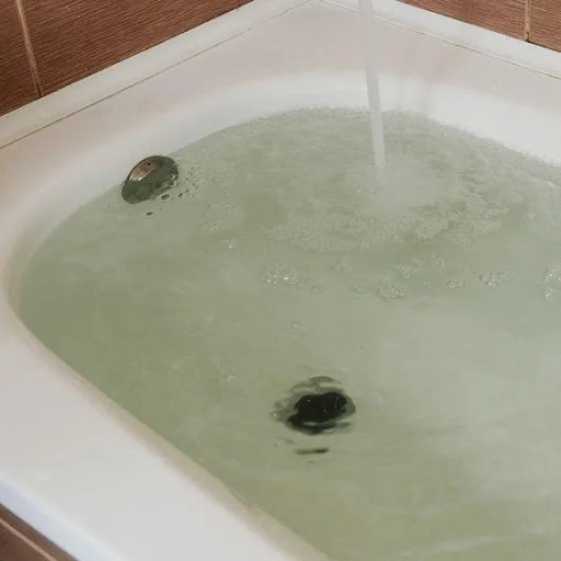 Bathroom Drain Cleaning Portland Or Plumber removing a bathtub stopper to clear a hair clog