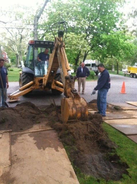 Small access hole dug in a yard for trenchless sewer pipe repair